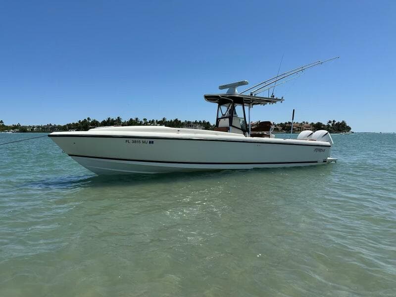 2004 Intrepid 32 Cuddy boat on calm water, clear sky, distant shoreline.