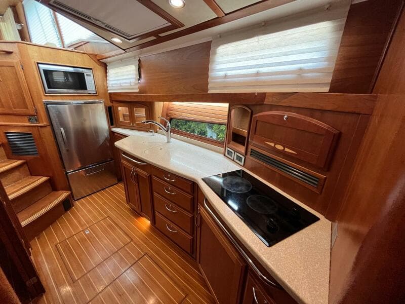 Luxurious 2013 Sabre 48 Salon Express yacht kitchen with wood cabinetry and modern appliances.