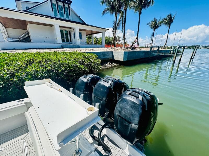 2000 Luhrs Tournament 320 Open boat docked near waterfront house with palm trees.