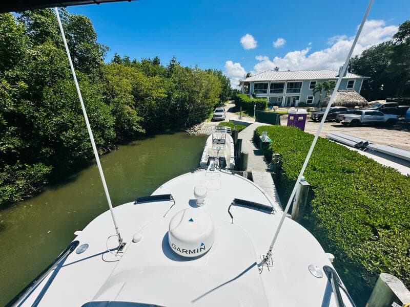 2000 Luhrs Tournament 320 Open boat docked near a canal with lush greenery.
