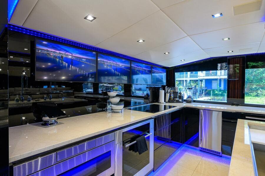 Luxurious kitchen interior of 1997 Broward 108 Raised Pilothouse yacht with modern appliances and blue LED lighting.