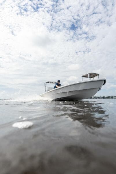 2025 BlueZones Boatworks 16' Flats boat cruising on open water under cloudy sky.