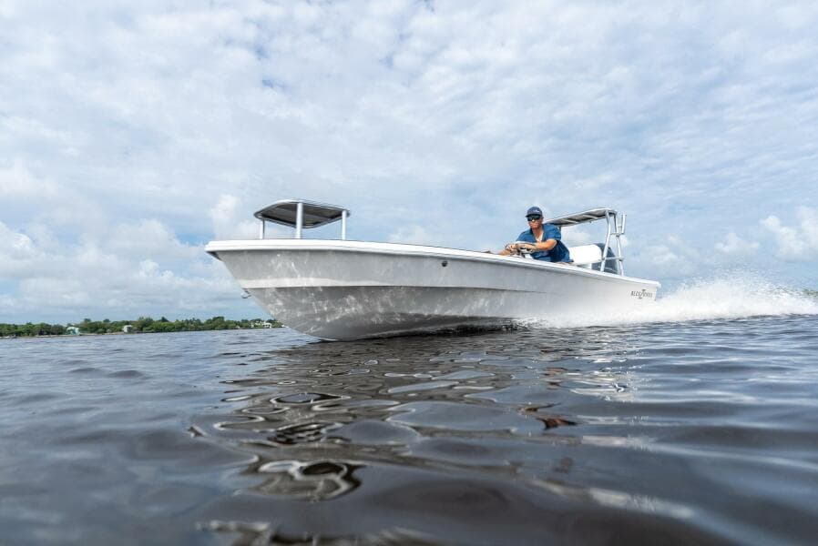 2025 BlueZones Boatworks 16' Flats boat cruising on open water under a cloudy sky.