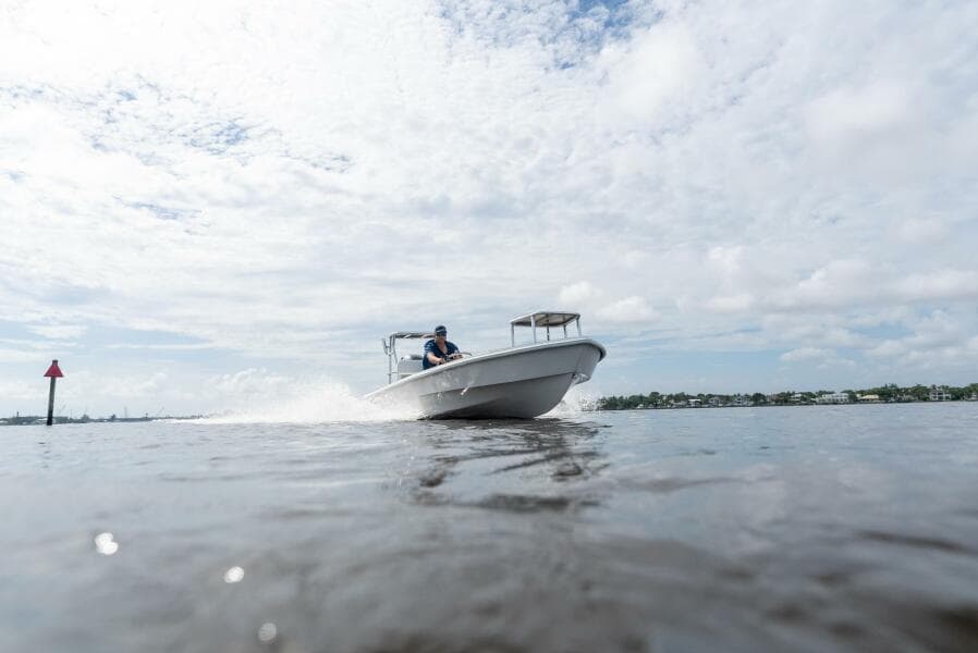 2025 BlueZones Boatworks 16' Flats boat cruising on open water under cloudy sky.