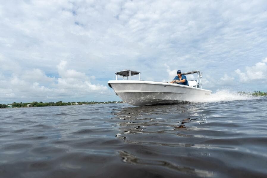 2025 BlueZones Boatworks 16' Flats cruising on open water under a cloudy sky.