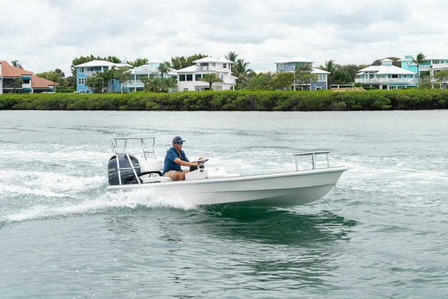 2025 BlueZones Boatworks 16' Flats cruising on water near coastal homes.
