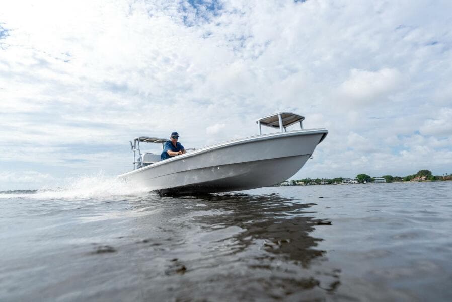 2025 BlueZones Boatworks 16' Flats boat cruising on open water under a cloudy sky.