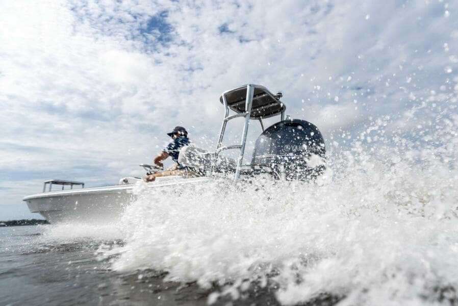 2025 BlueZones Boatworks 16' Flats speeding through water, creating splashes under a cloudy sky.