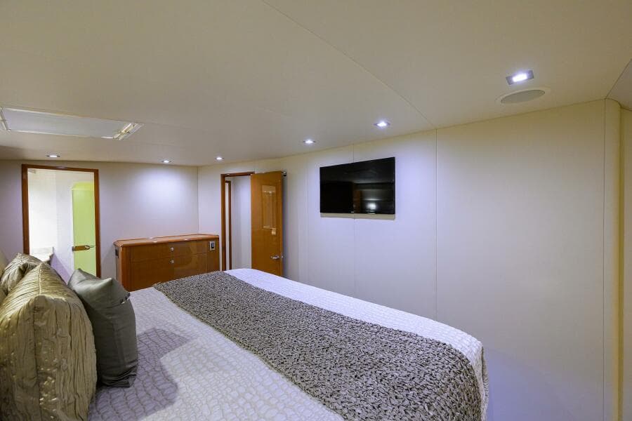 Luxurious bedroom interior of 2004 Viking 65 Enclosed Bridge yacht with TV and modern lighting.