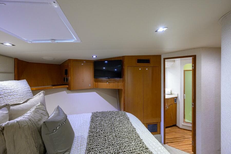Luxurious bedroom interior of 2004 Viking 65 Enclosed Bridge yacht with TV and ensuite bathroom.