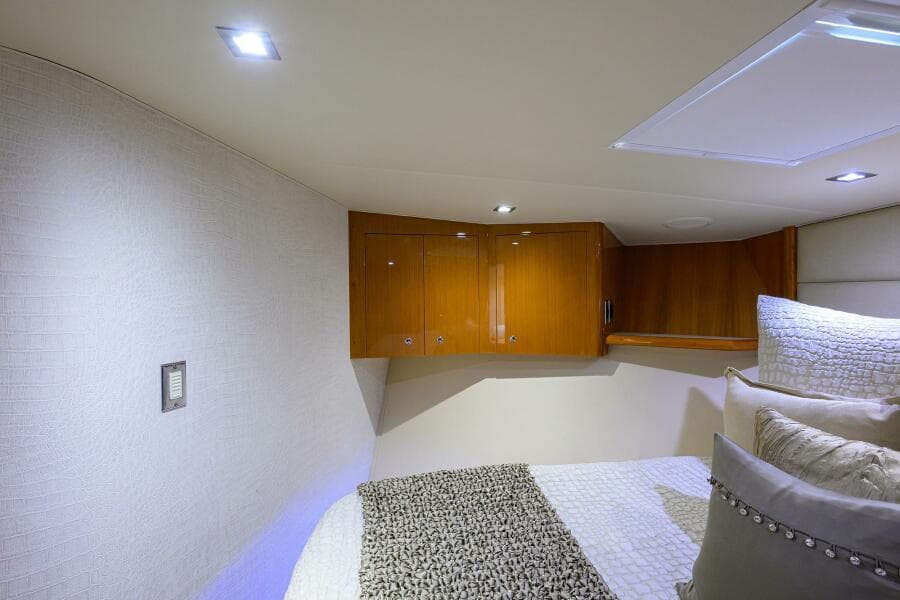 Interior cabin of 2004 Viking 65 Enclosed Bridge yacht with wooden cabinets and cozy bedding.