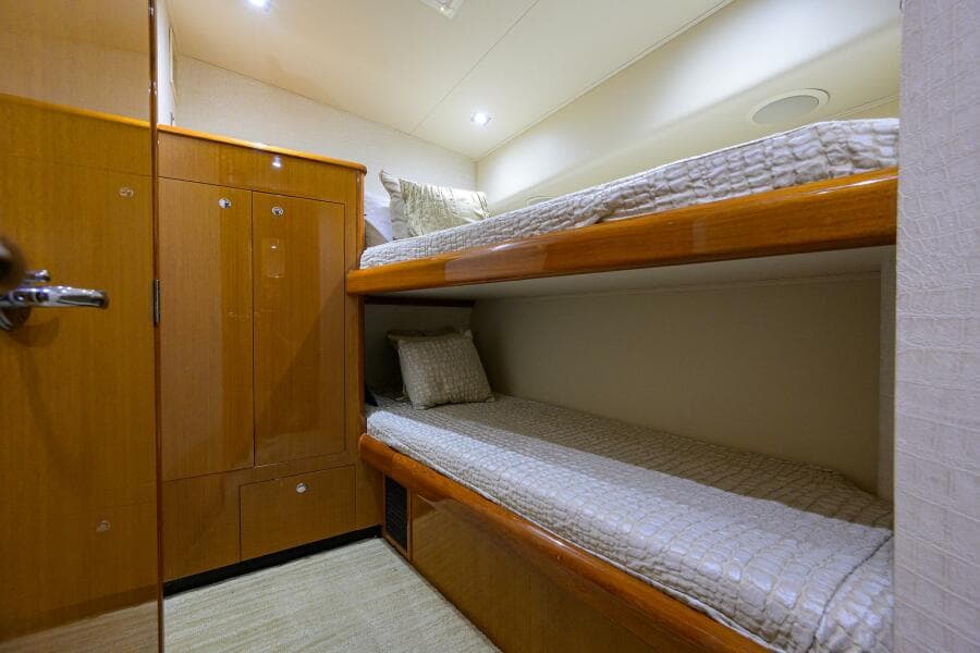 2004 Viking 65 Enclosed Bridge w/Tower cabin with bunk beds and wooden cabinetry.