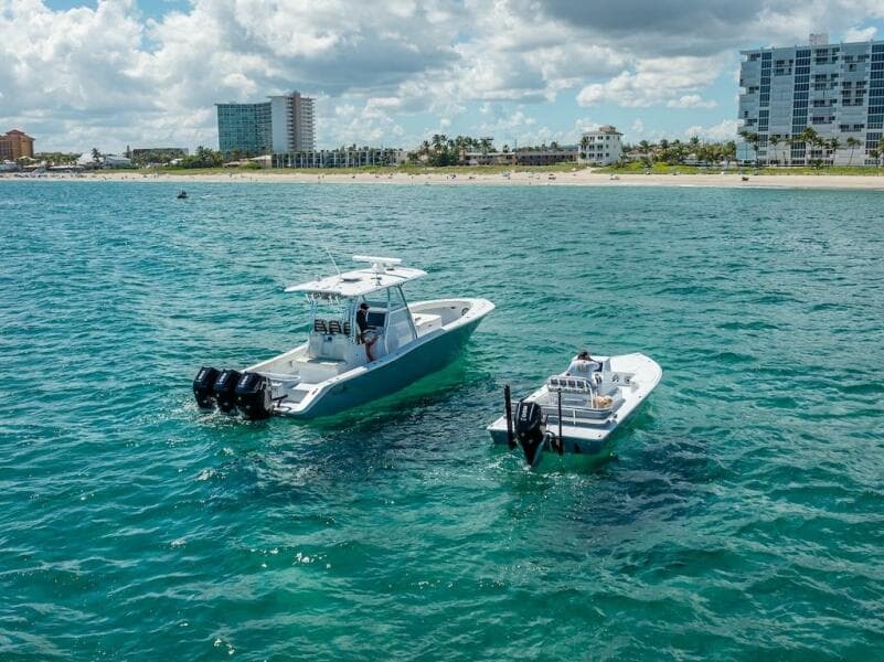 2025 Billfish 39 Center Console with Tower on ocean near beach and buildings.