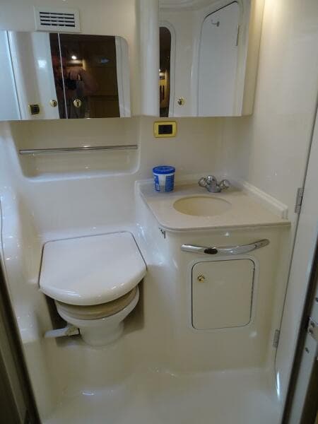 2001 Sea Ray 410 Sundancer bathroom with toilet, sink, and storage.