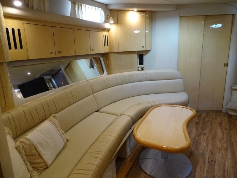 Interior of 2001 Sea Ray 410 Sundancer with beige leather seating and wooden table.