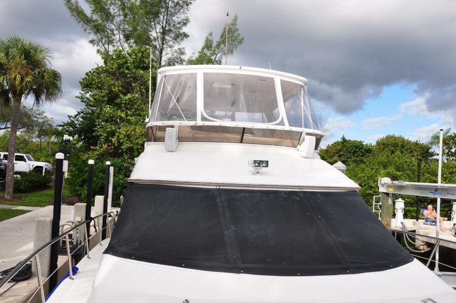 1998 Sea Ray 480 Sedan Bridge docked, front view with canopy and lush background.