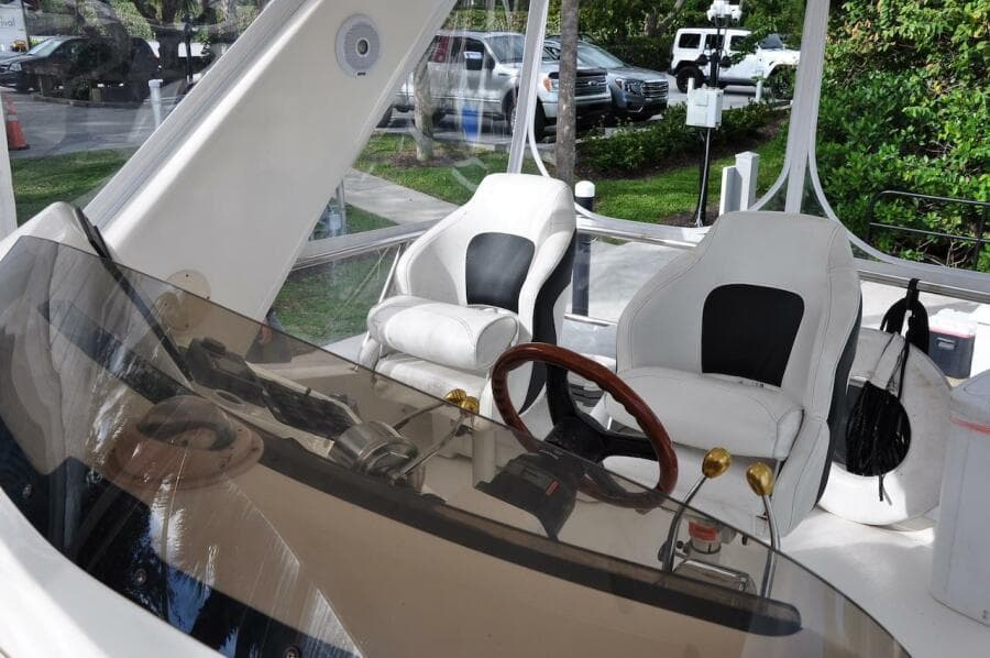 1998 Sea Ray 480 Sedan Bridge helm with dual captain chairs and wooden steering wheel.