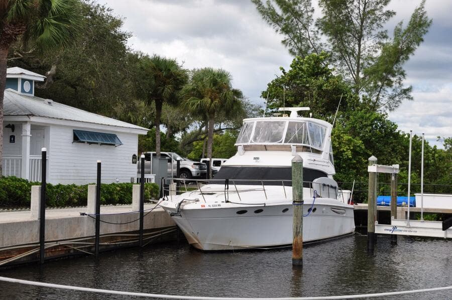 1998 Sea Ray 480 Sedan Bridge docked at a marina with lush greenery.