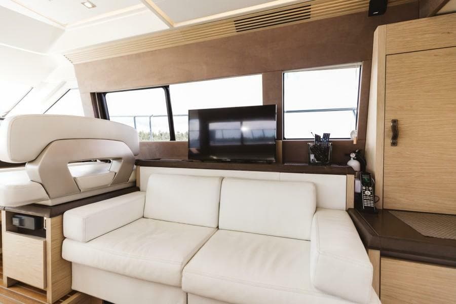 Luxurious interior of 2015 Beneteau Monte Carlo 5 yacht with white sofa and TV.