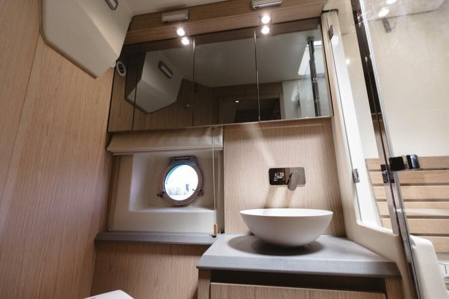 Luxurious bathroom in 2015 Beneteau Monte Carlo 5 yacht with modern fixtures and porthole window.