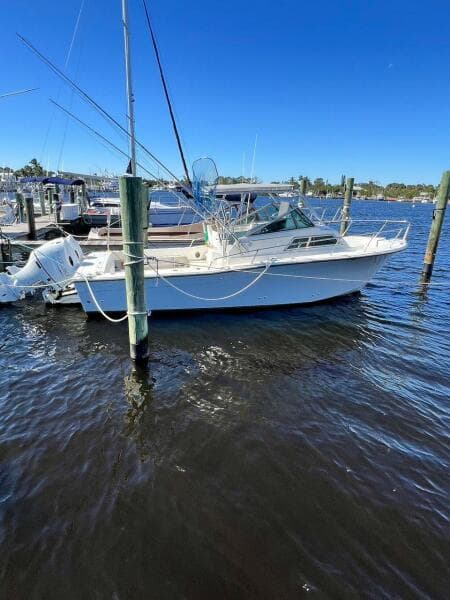 1988 Grady-White 25 SAILFISH boat docked on calm water under clear blue sky.