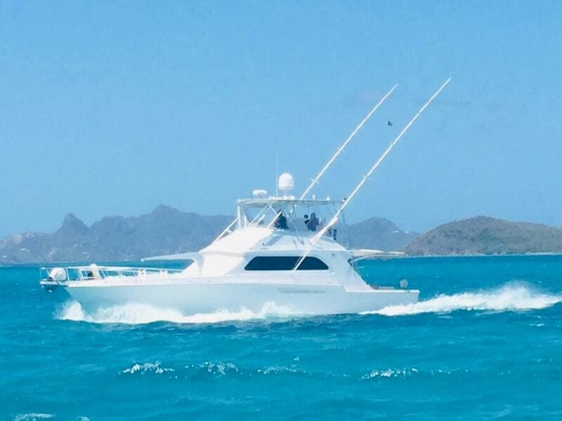 1988 Bertram 54' yacht cruising in turquoise waters with scenic island backdrop.