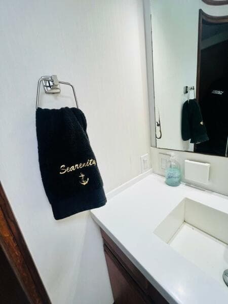 Bathroom interior of 1988 Bertram 54' yacht with "Searenity" towel and modern sink.