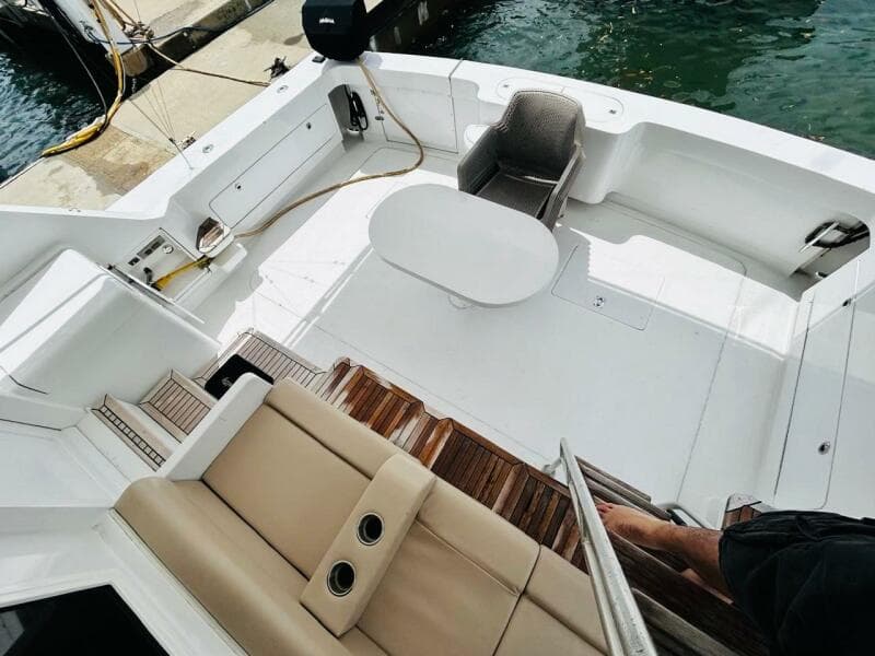 1988 Bertram 54' yacht deck with seating and table, docked at marina.
