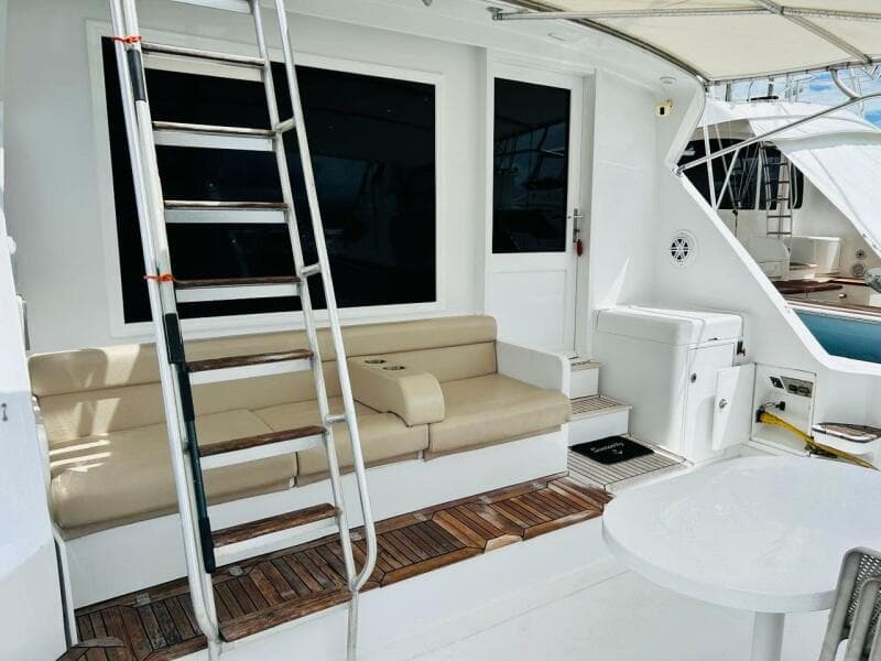 1988 Bertram 54' yacht deck with seating, ladder, and table.