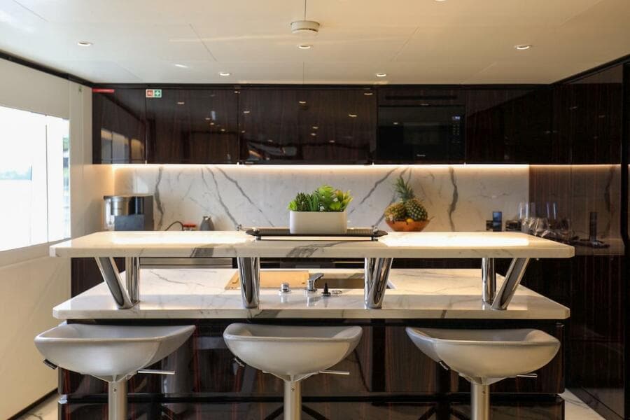 Luxurious yacht kitchen with marble countertops, modern stools, and elegant cabinetry, Majesty 120, 2025.