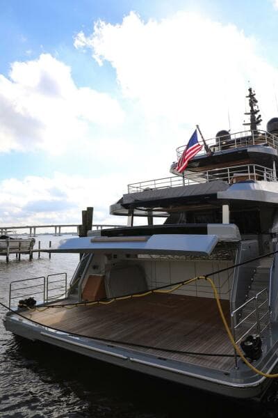 Luxury Majesty 120 yacht, 2025 model, docked with American flag, under a bright sky.