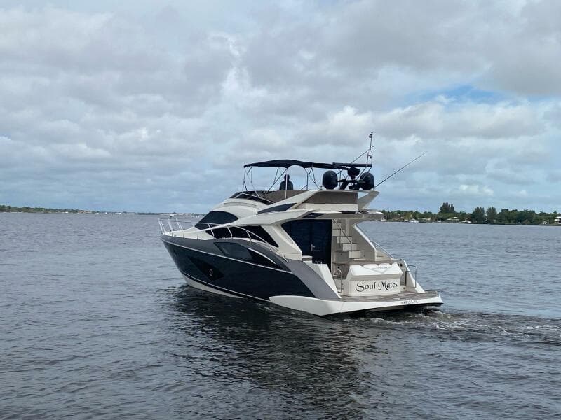2017 Marquis 500 Sport Yacht cruising on a calm lake under a cloudy sky.