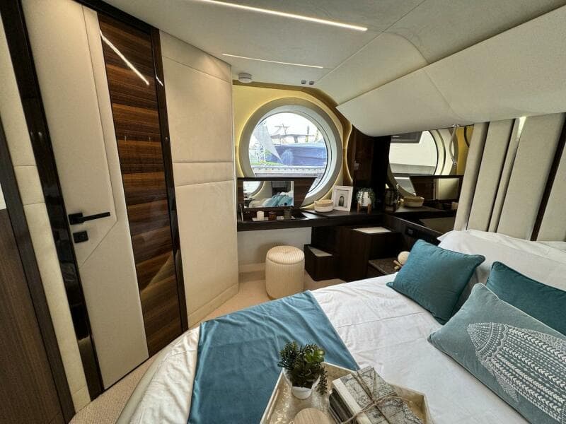 Luxurious 2024 Aicon 66 Vivere yacht bedroom with elegant decor and round window view.