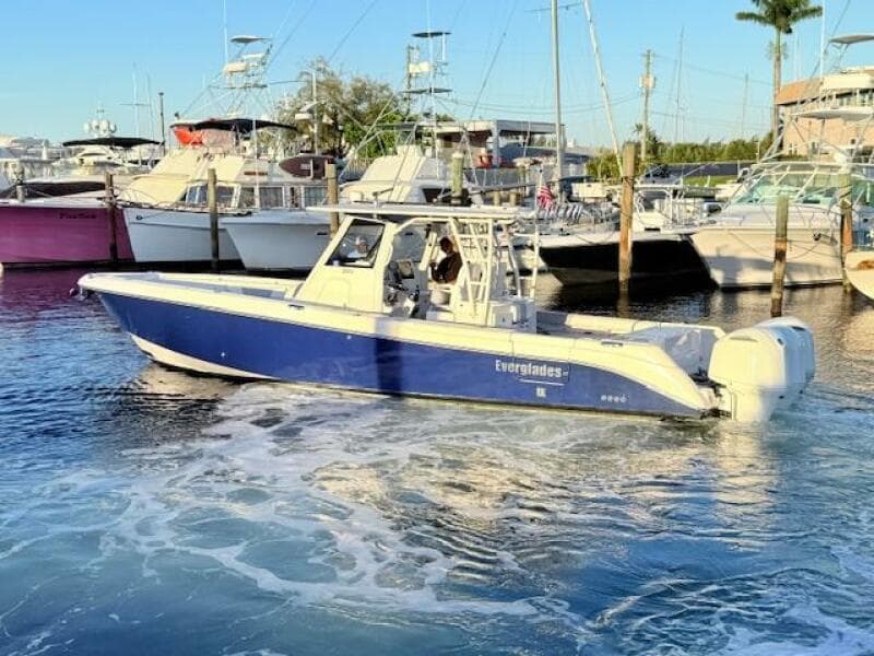 2014 Everglades 355 Center Console boat docked in marina, blue hull, calm waters.