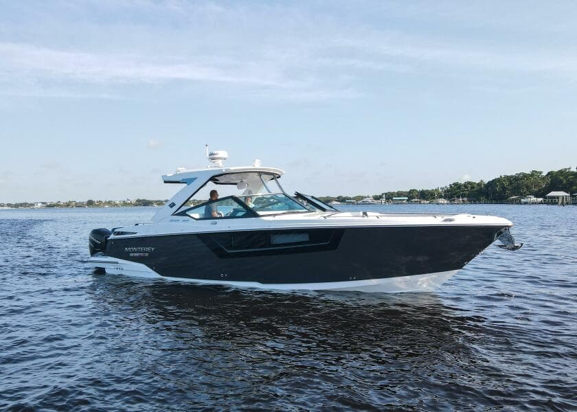 2023 Monterey 385 Super Sport boat cruising on a calm lake under a clear sky.