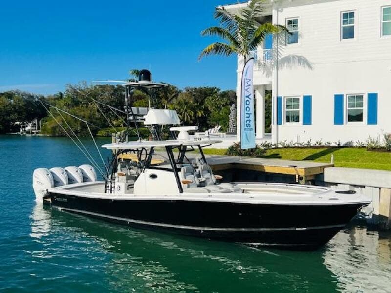 2024 Regulator 41 boat docked by a waterfront house with palm trees.