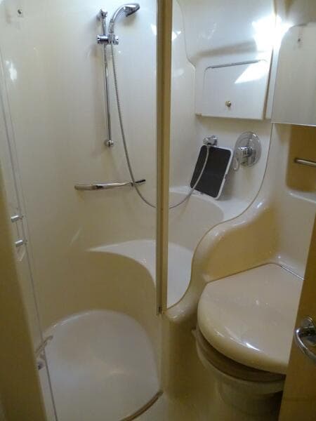 2001 Sea Ray 410 Sundancer bathroom with shower, toilet, and storage cabinet.