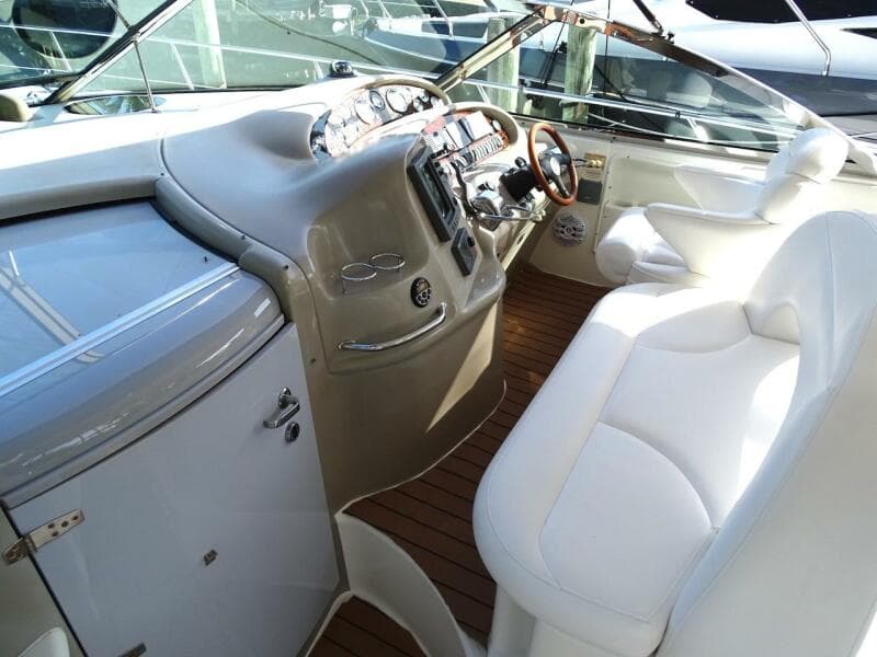 2001 Sea Ray 410 Sundancer helm with white seating and wooden flooring.
