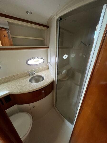 2000 Carver 396 Motor Yacht bathroom with sink, shower, and storage shelves.