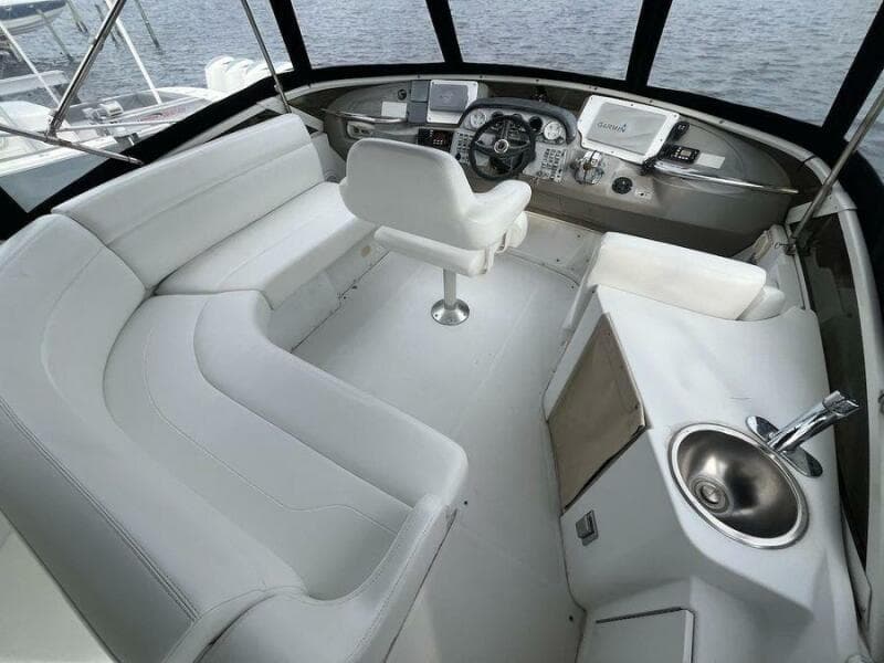 2000 Carver 396 Motor Yacht cockpit with white seating, steering console, and sink.