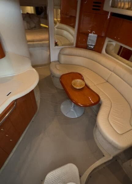 Interior of 2001 Sea Ray 380 Sundancer with curved seating and wooden table.