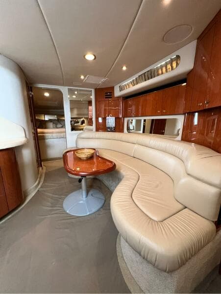 Interior of 2001 Sea Ray 380 Sundancer with curved leather seating and wooden table.