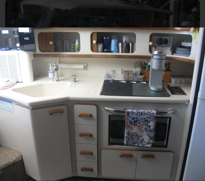 Interior of 1993 Sea Ray 440 Sundancer yacht kitchen with sink, stove, and storage.
