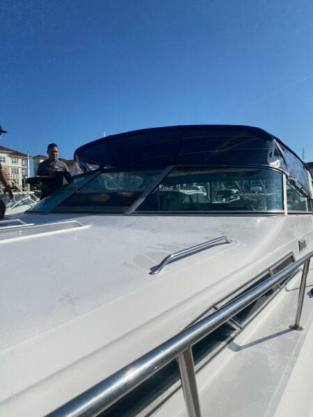 1993 Sea Ray 440 Sundancer yacht with sleek design and blue canopy under clear sky.