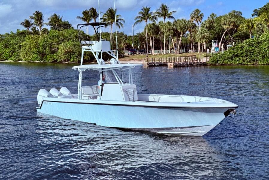 2024 Contender 39 ST boat cruising on a scenic waterway with palm trees in the background.