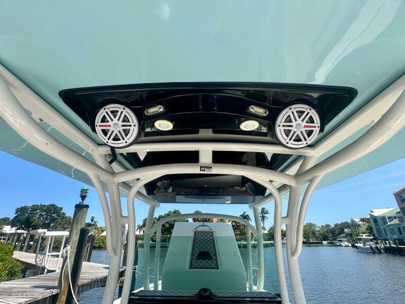 2019 Wellcraft 262 Fisherman boat with speakers and canopy, docked by a scenic waterfront.