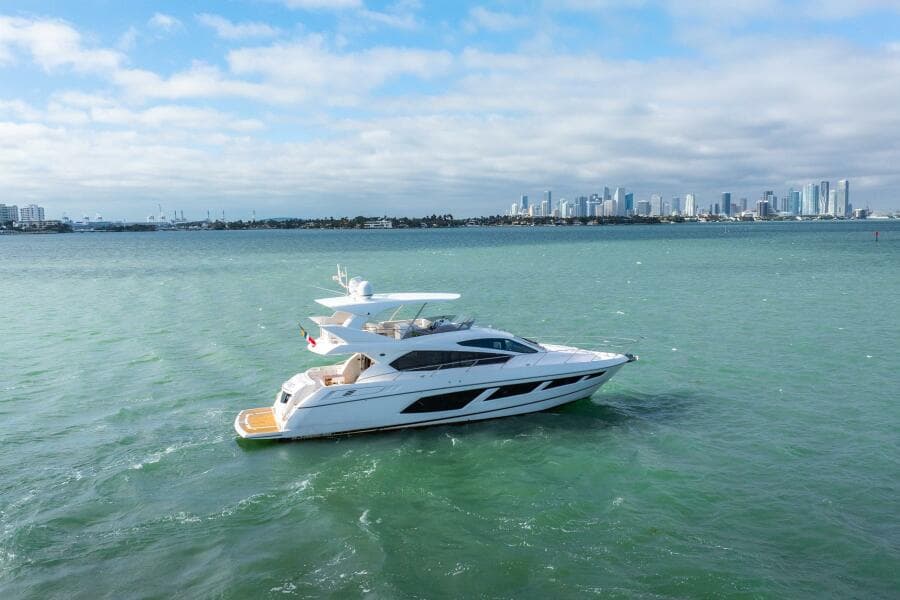 2016 Sunseeker Manhattan 65 yacht cruising on open water with city skyline backdrop.