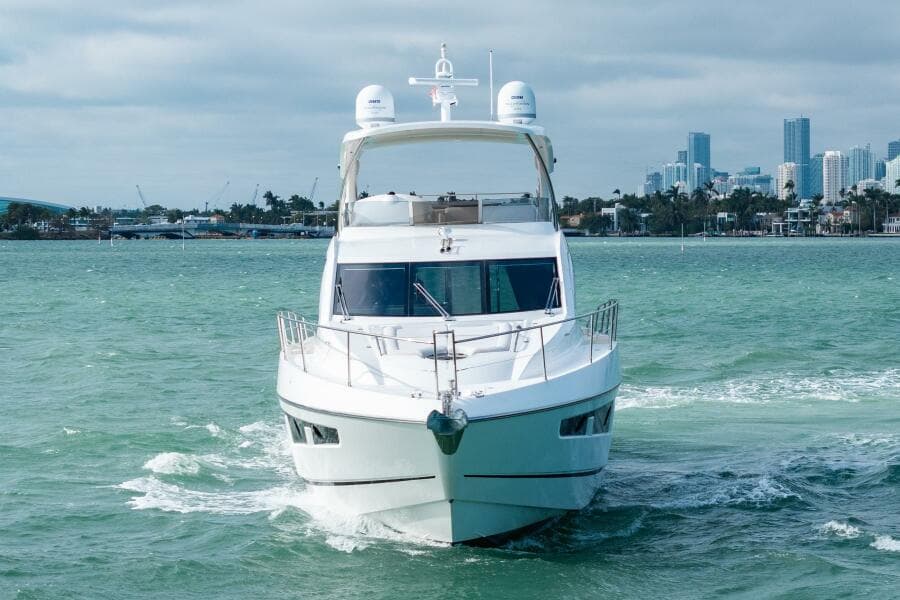 2016 Sunseeker Manhattan 65 yacht cruising in open water with city skyline backdrop.