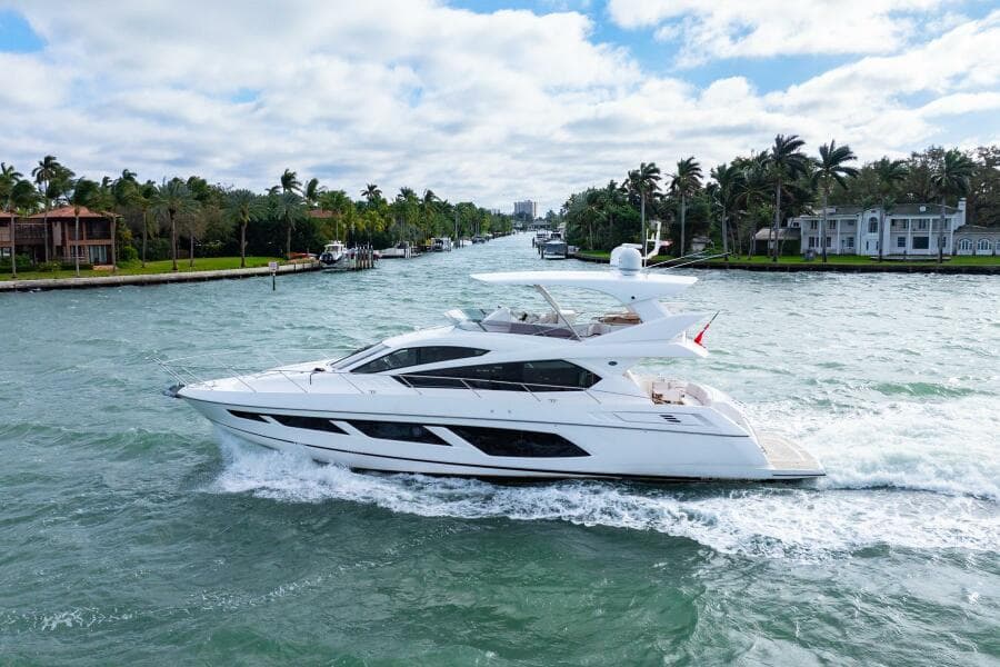 2016 Sunseeker Manhattan 65 yacht cruising on a scenic waterway with palm trees.