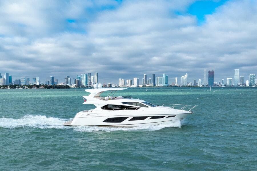 2016 Sunseeker Manhattan 65 yacht cruising near city skyline.